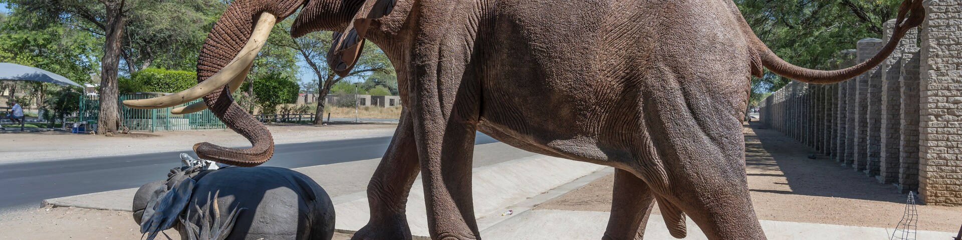 Uma grande estátua de elefante com presas, rodeada por diversas esculturas e um cercado.