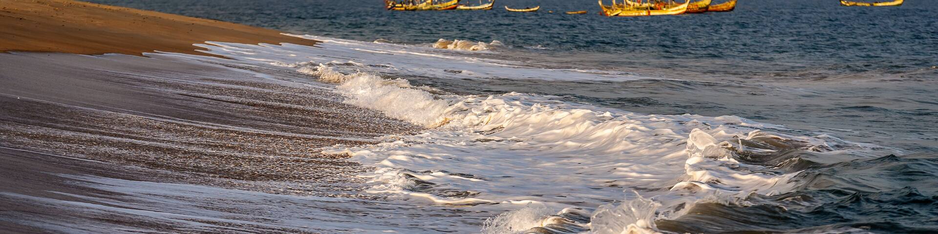 Sunset over Ghana's coast keta with foaming waves and fishing boats in the background
