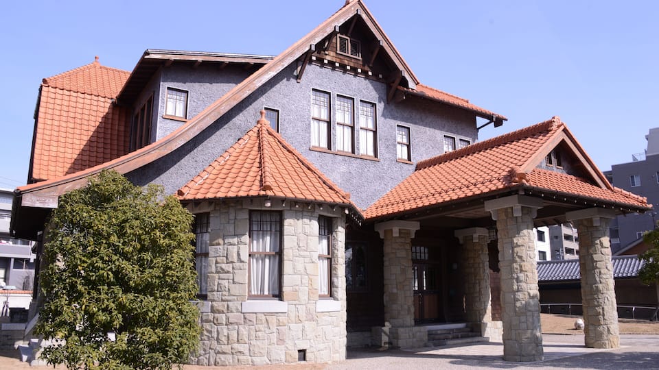 A large stone house with a red-tiled roof and a stone porch.