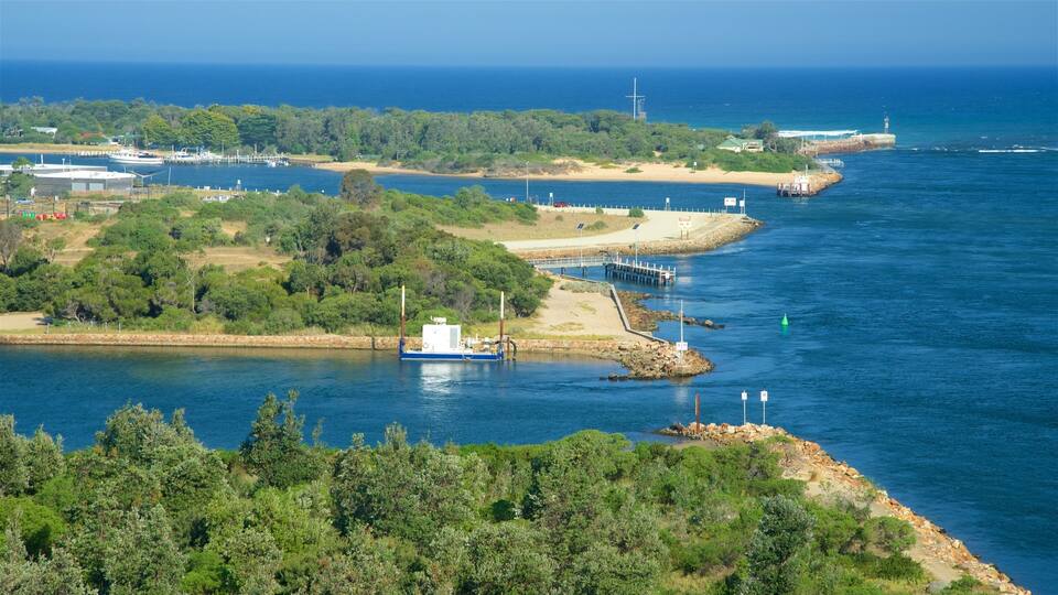 A coastal landscape with a pier, a boat docked at the pier, and a lighthouse in the distance.