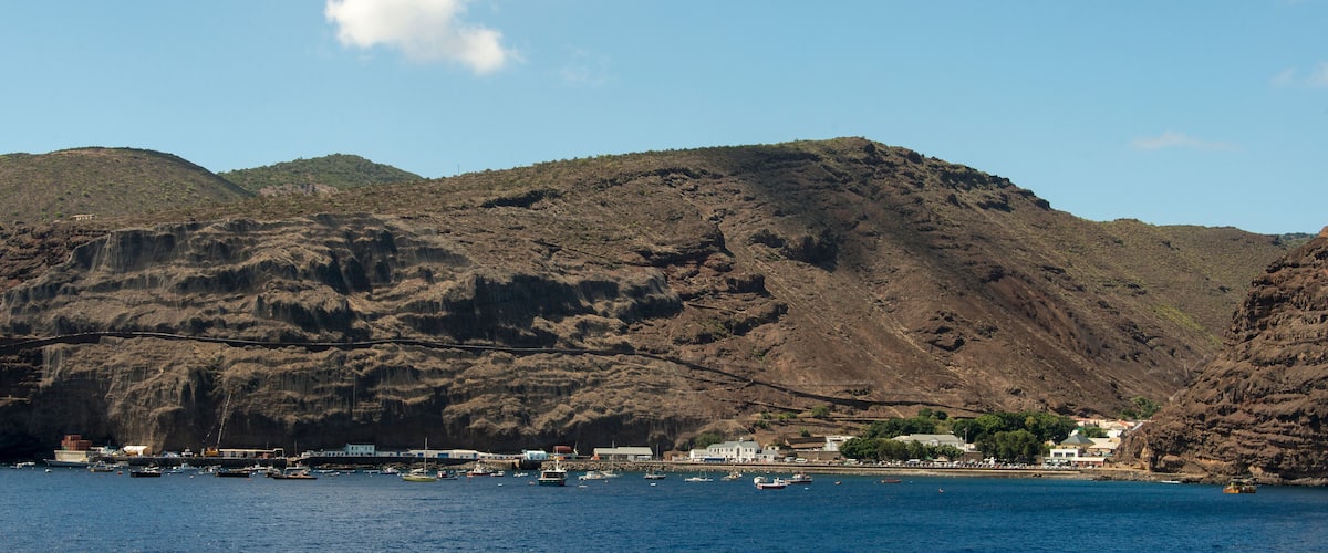A coastal town with a rocky hillside and a harbor filled with boats.