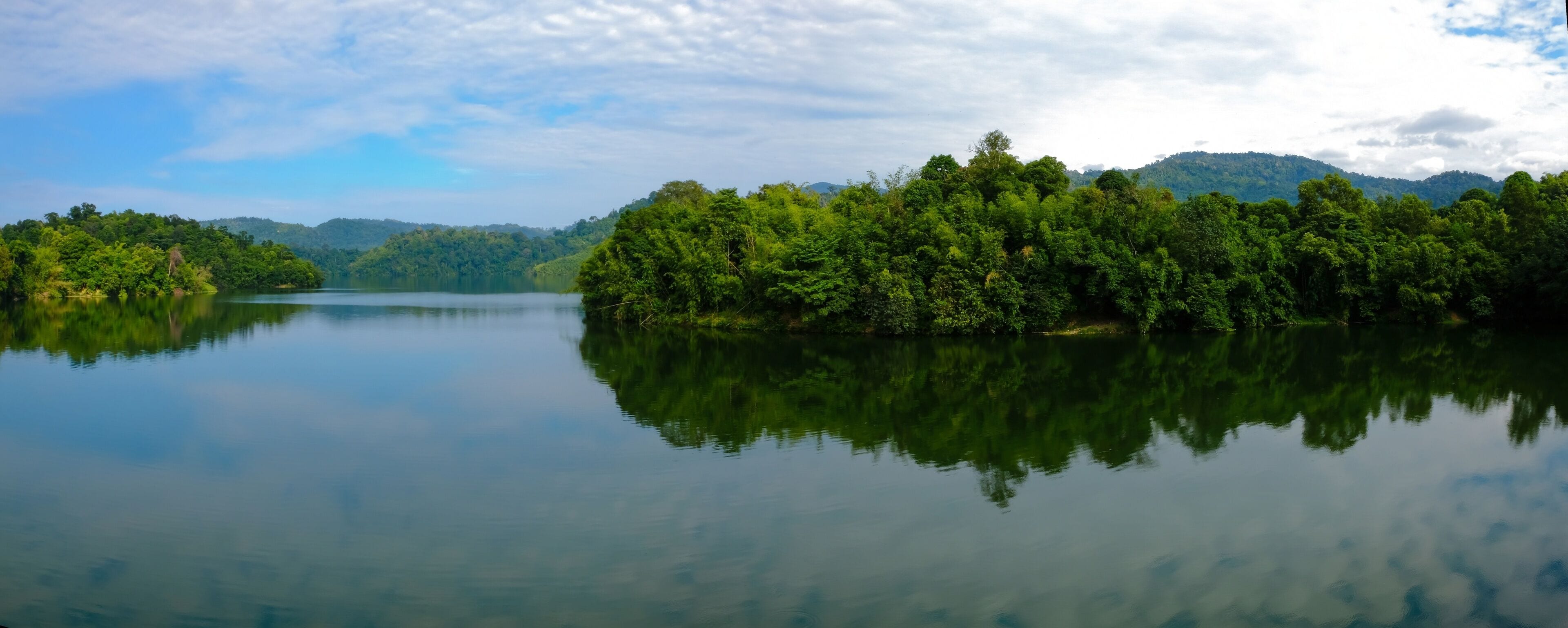 Panoramic shot of dam water surrounded with green trees in Kuala Kubu Bharu, Selangor, Malaysia.