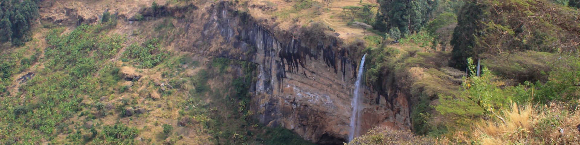 Tall and thin Sipi Falls flowing among rocks in Uganda