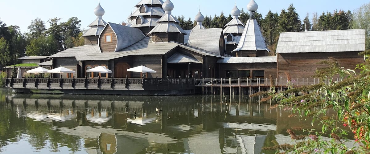 Pairi Daiza is a big animal park, located on the site of the former Abbey of Cambron, where visitors make a trip along the 5 continents and discover more than 5,000 animals. In May 2018 Pairi Daiza received the prize for “Best animal park in Europe” at the presentation of the Diamond Theme Park Awards, also known as the Oscars of the theme parks and zoos.
The photo shows Restaurant The Izba.
Izba (изба) means in Russian: wooden house in the countryside. The Izba in Pairi Daiza is inspired by traditional Russian architecture, with its roof tiles and domes, which are also made entirely of wood! It is an immense restaurant (1.100 m² covered and a terrace of 400 m²) with a cosy atmosphere and the decoration refers to fairy tales and legends from Russian folklore.