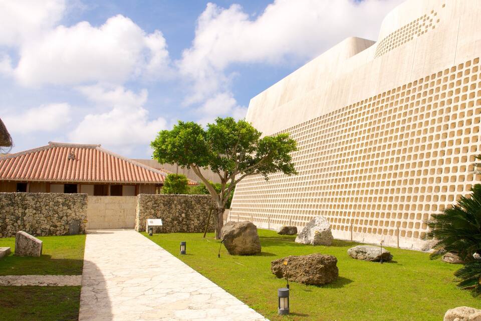 A courtyard with a stone pathway, large rocks, a tree, and a building with a tiled roof.
