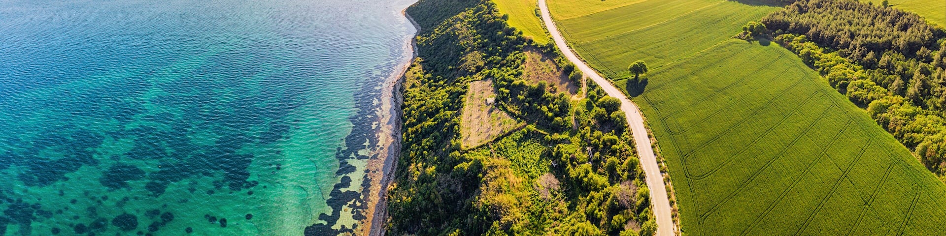 aerial perspective of the vibrant landscape where lush green fields meet the turquoise waters of the Mediterranean Sea at Dardanelles strait