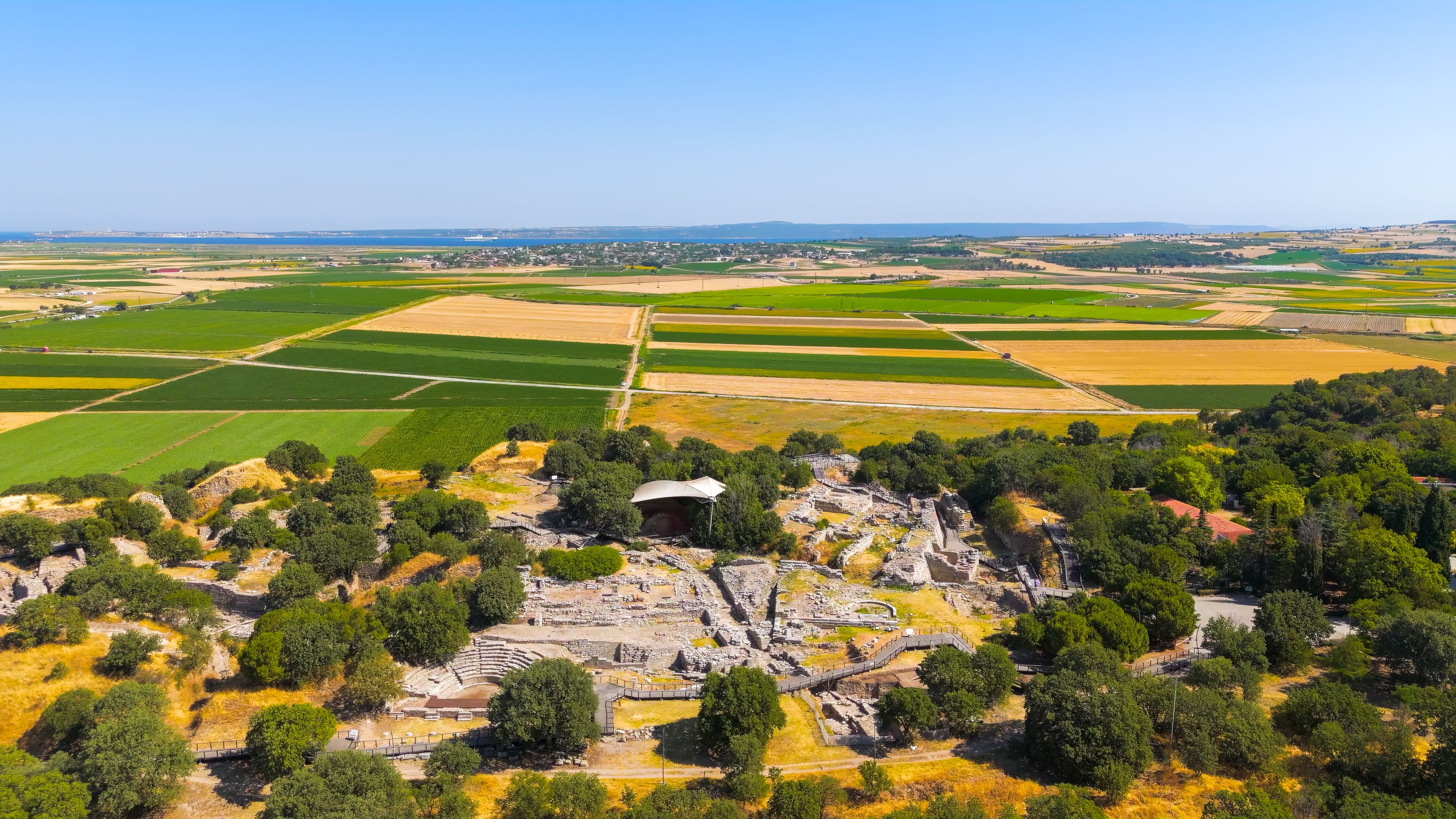 An ancient amphitheater surrounded by fields and trees.