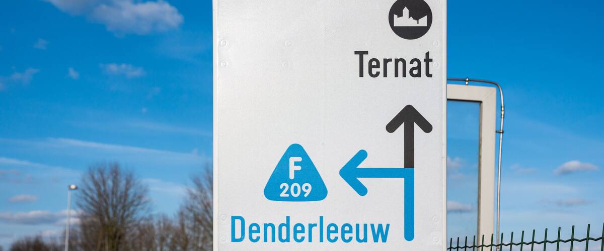 A road sign with directions to Ternat and Denderleeuw, indicating a distance of 60m.