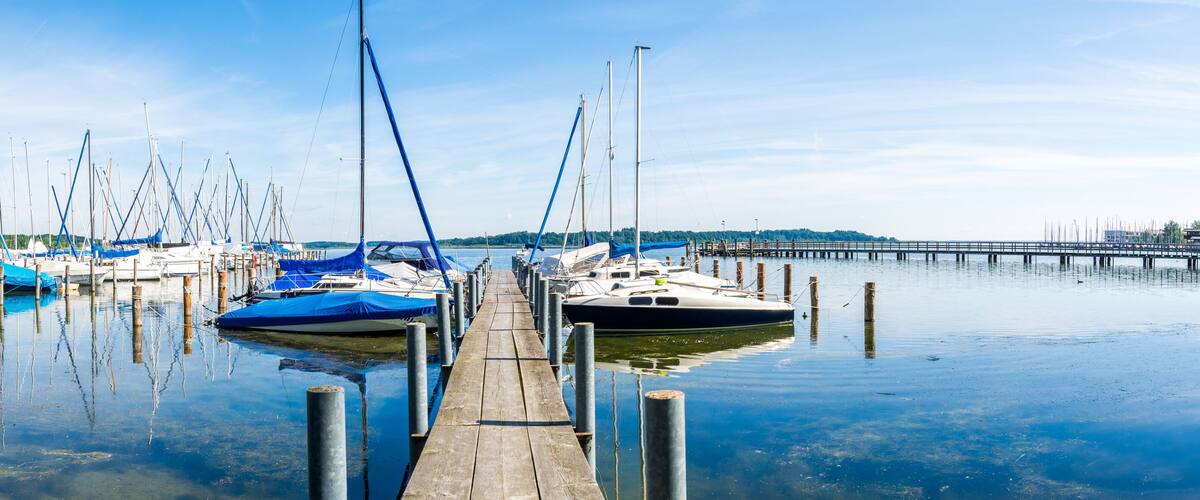 A marina with multiple sailboats docked at wooden piers.