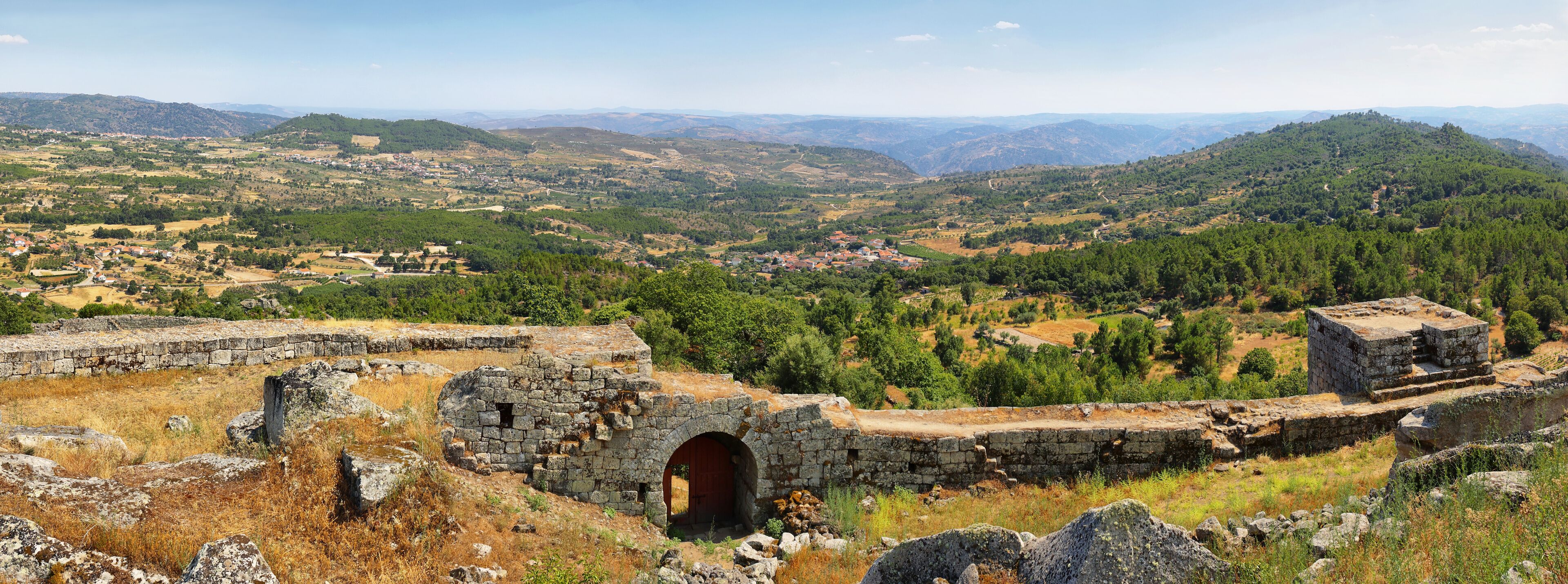 A mountainous landscape with ancient stone ruins and a small village in the valley.