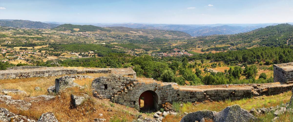 A mountainous landscape with ancient stone ruins and a small village in the valley.