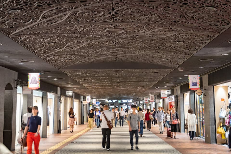 En livlig indendørs handelsgang med dekorative loftsmønstre og butikker på hver side.