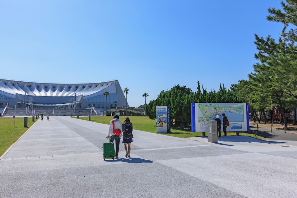 A modern building with a unique curved roof, a pathway, and a map sign.