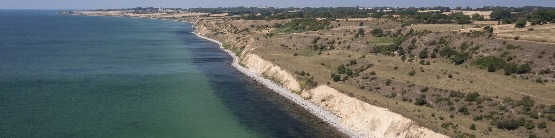 Aerial view of the striking contrast between the turquoise sea and the rugged coastline, a symphony of natural beauty unfolds, Aeroskobing, Southern Denmark, Denmark.