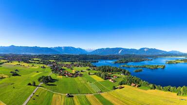 A lake surrounded by green fields and mountains.
