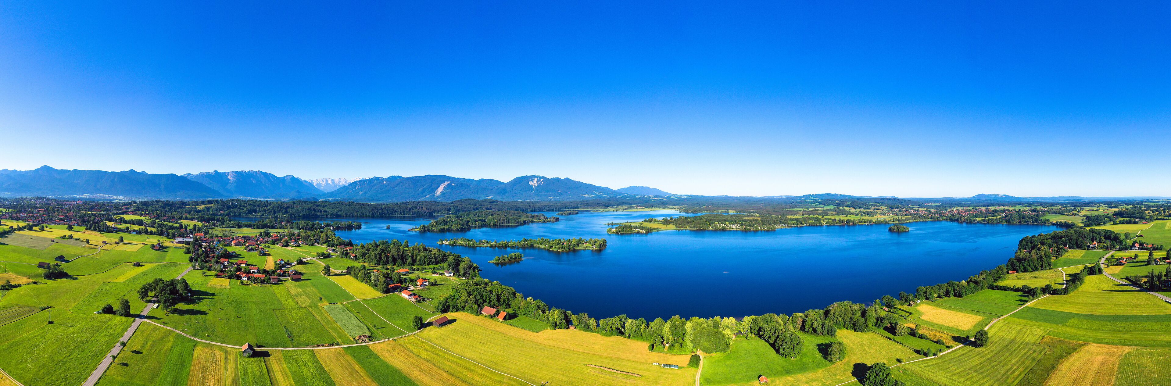 A lake surrounded by green fields and mountains.