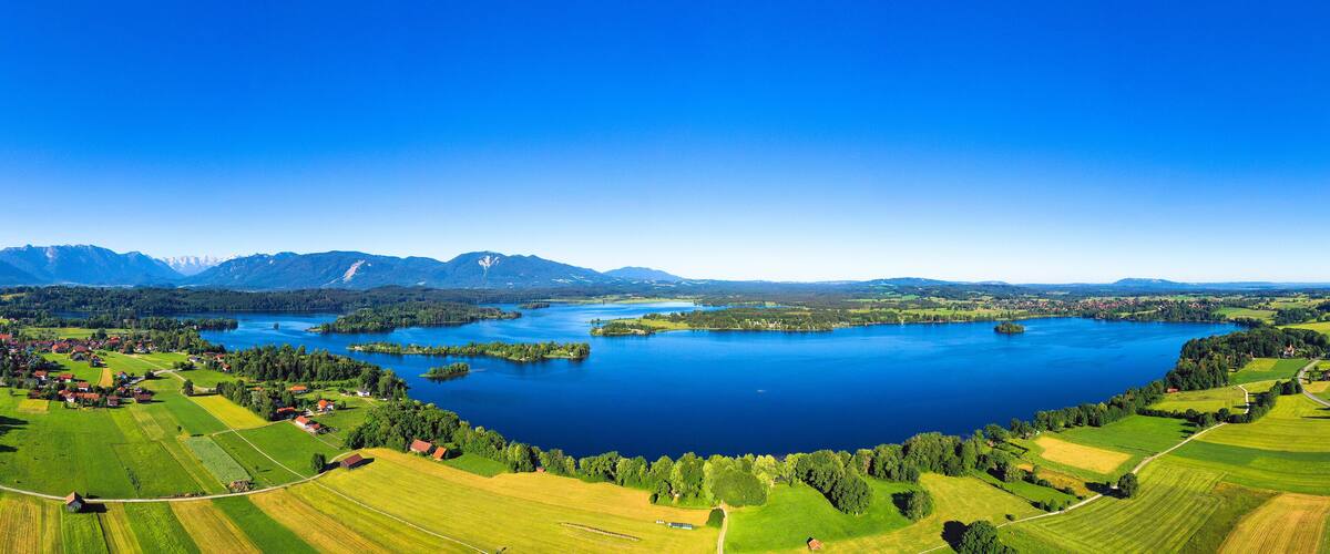 A lake surrounded by green fields and mountains.