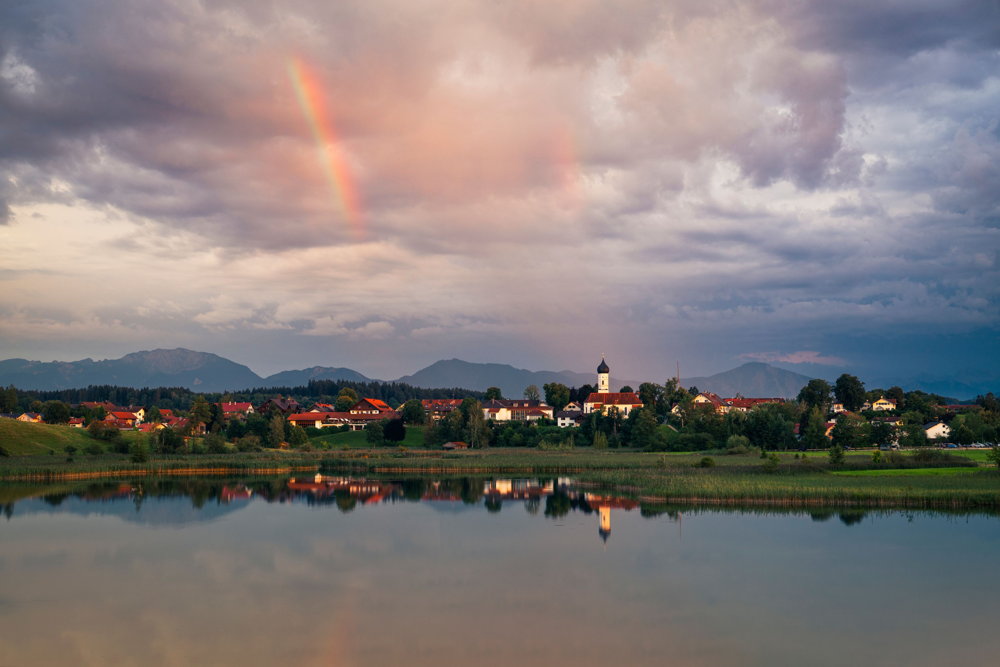 Regenwolken und Regenbogen bei Sonnenuntergang über den Bayirschen Voralpen, Iffeldorf und dem Sengsee, Osterseen, Bayern, Deutschland