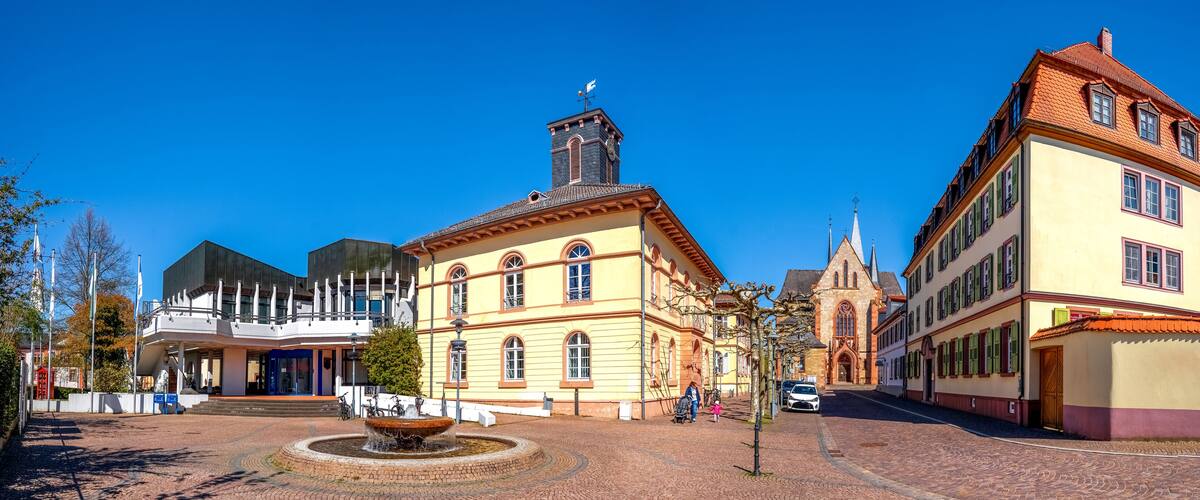 A historic town square with cobblestone streets, a fountain, and traditional European architecture.