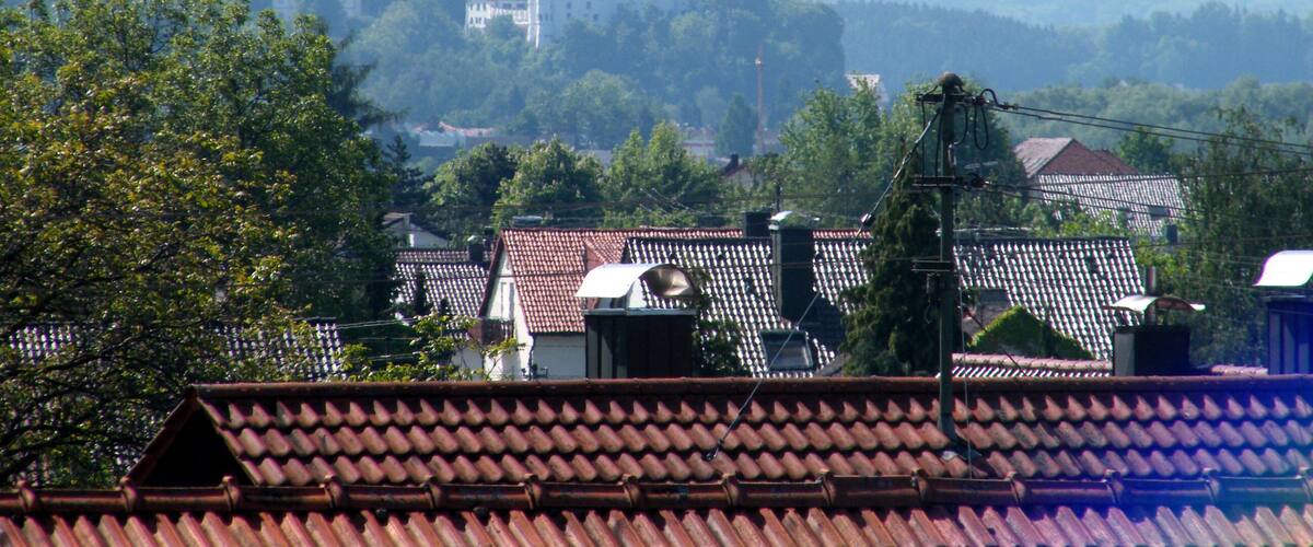 A castle on a hill with a red-tiled roof village in the foreground.