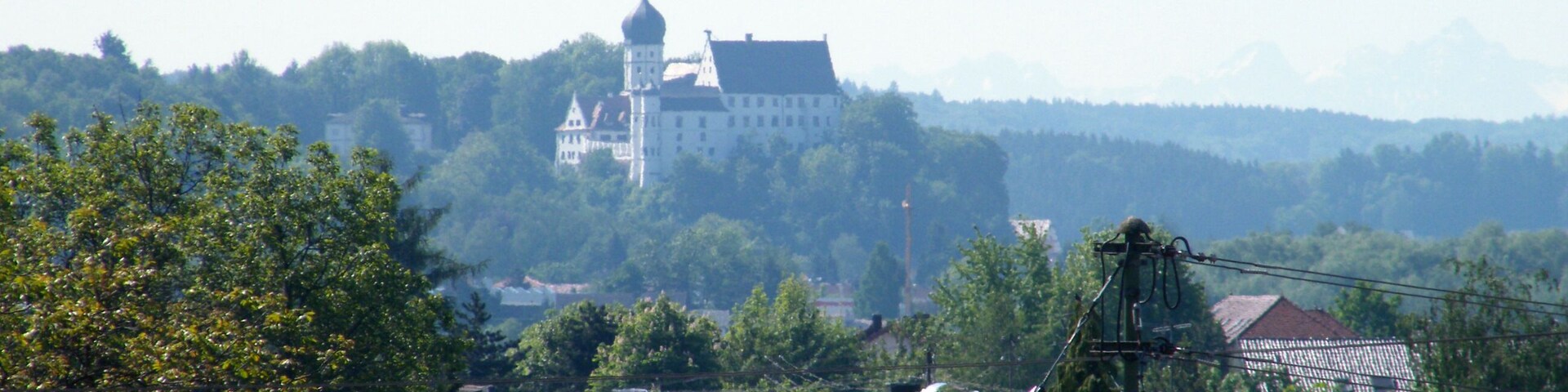 A castle on a hill with a red-tiled roof village in the foreground.