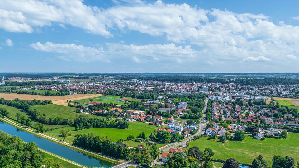 A river flowing through a town with green fields and scattered houses.