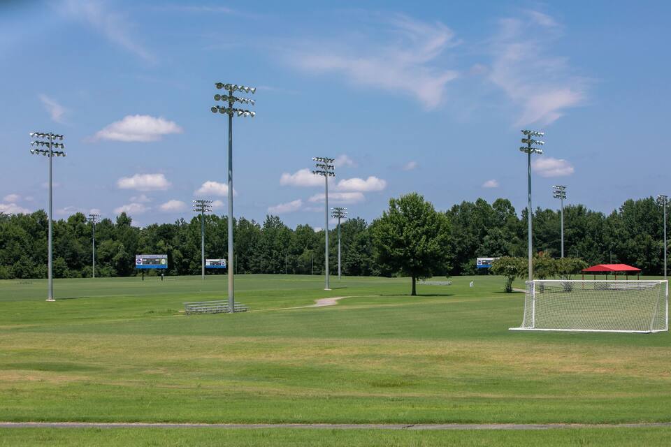 A soccer field with goalposts, floodlights, and a red canopy.