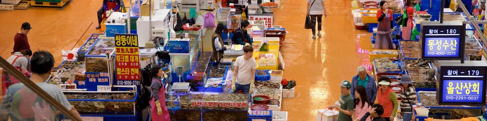 Mercado de Peixes Noryangjin mostrando mercados e comida assim como um pequeno grupo de pessoas
