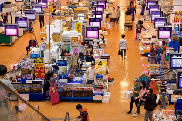 Mercado de Peixes Noryangjin mostrando mercados e comida assim como um pequeno grupo de pessoas