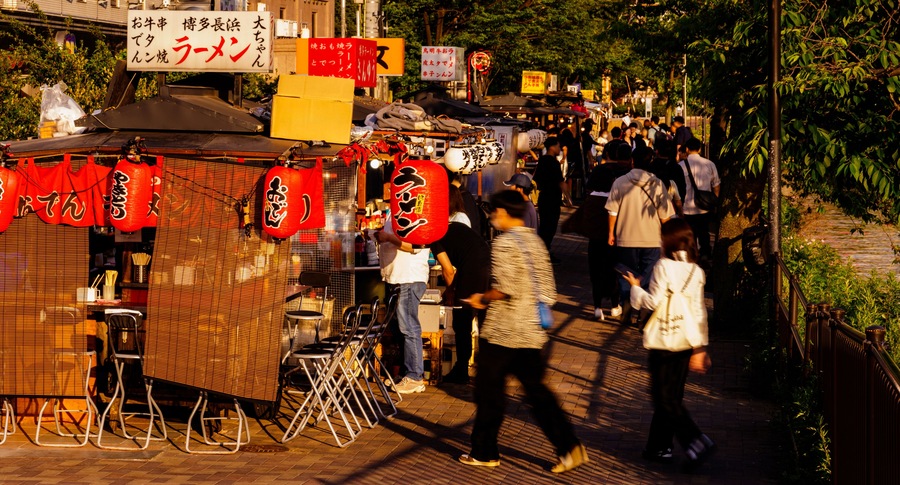 A bustling street market with food stalls and people walking.