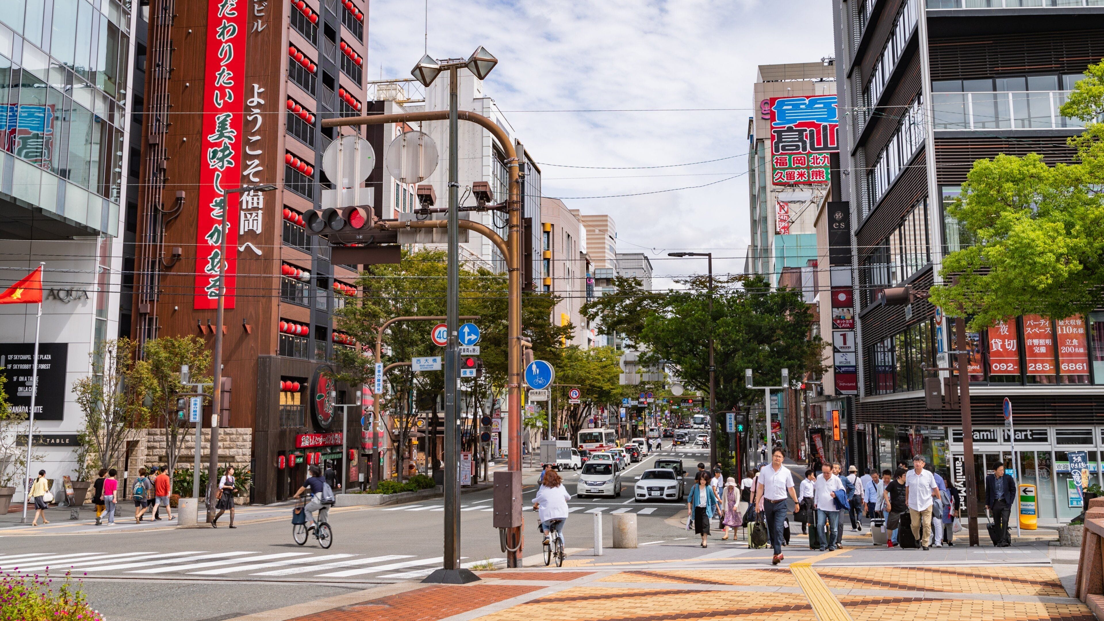 A busy urban street with pedestrians, cyclists, and cars.