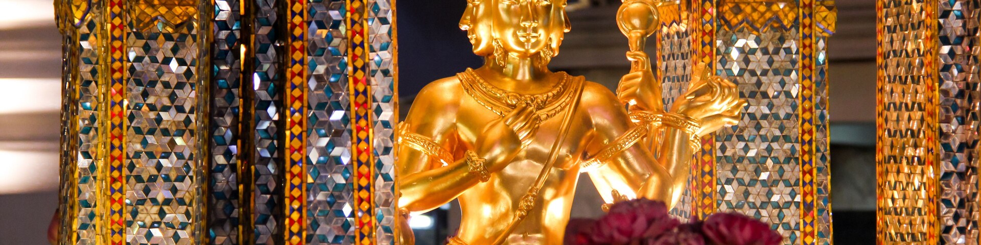 A golden statue of a seated figure, surrounded by intricately decorated pillars and columns.