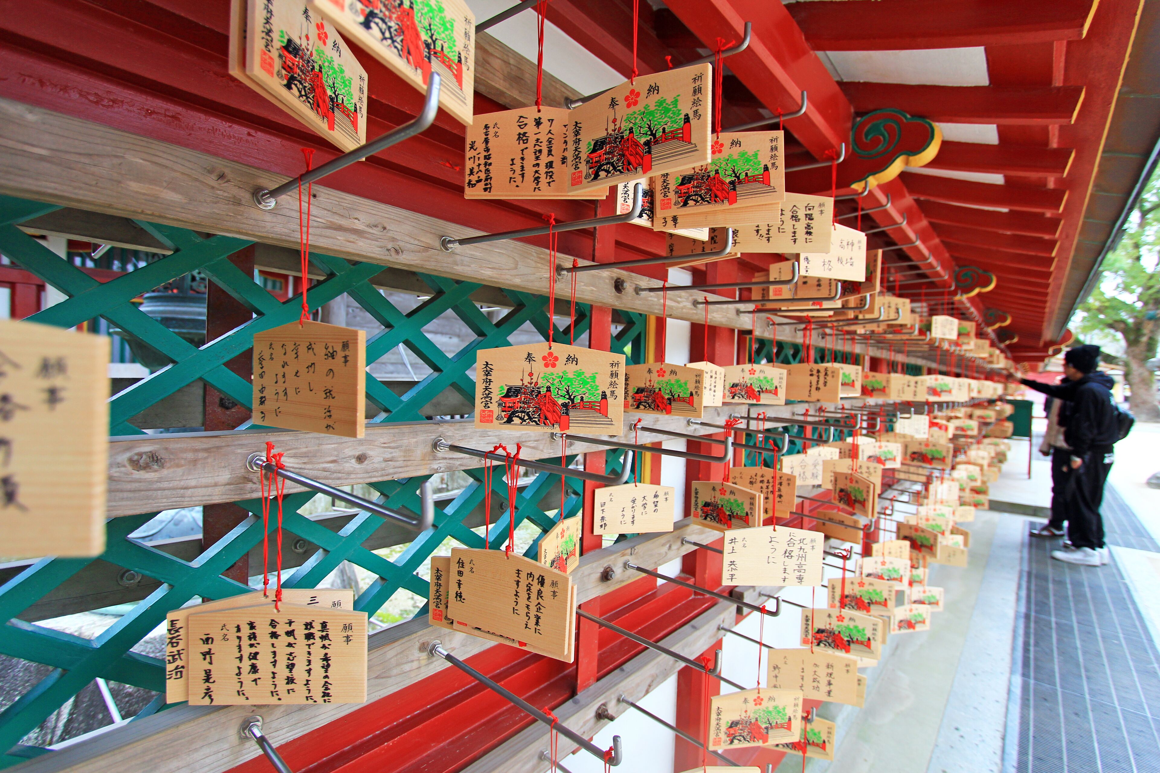 A series of wooden plaques with inscriptions hanging from a structure.