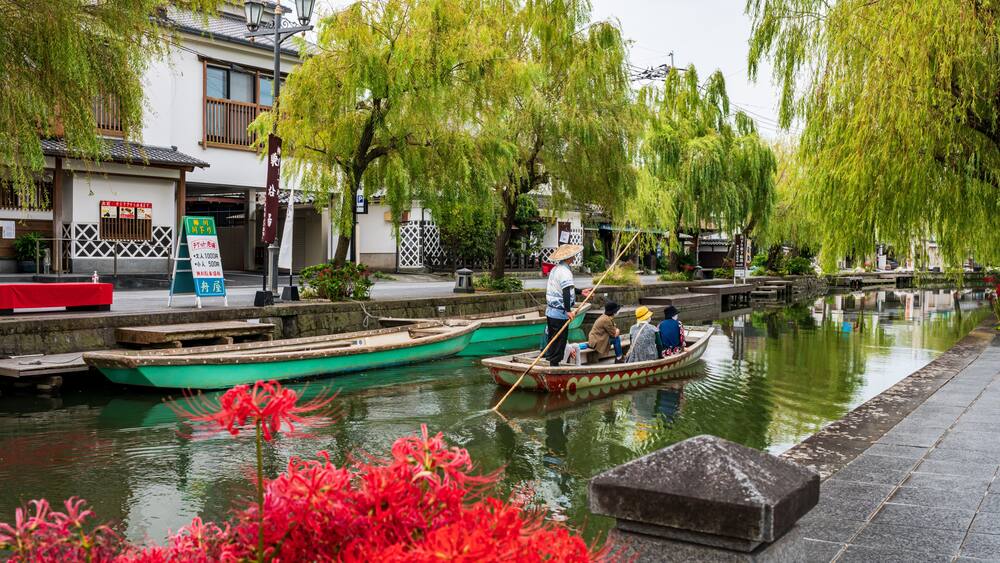 A traditional canal scene with boats, willow trees, and a building with signage.