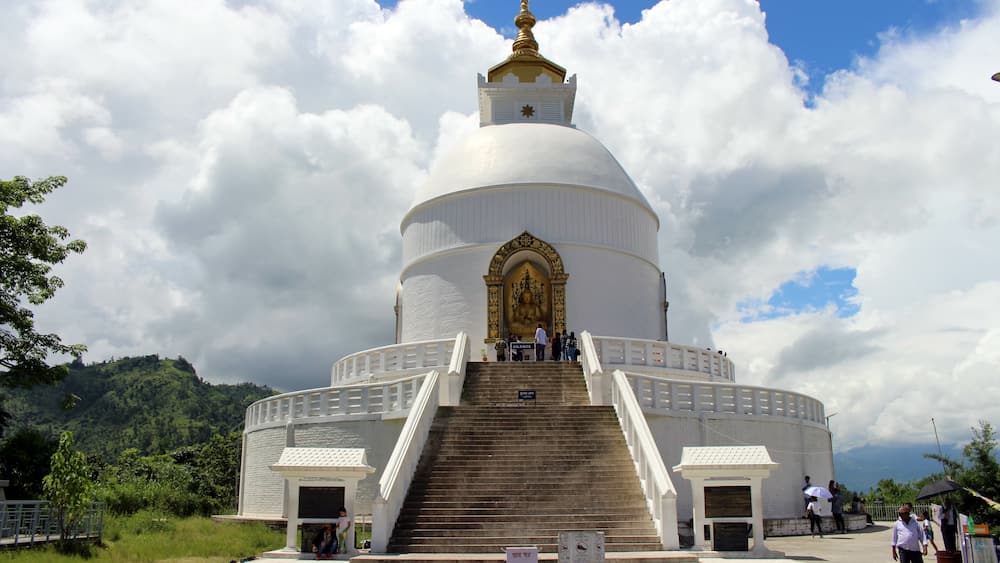 A white, domed building with a golden spire, surrounded by a white fence and stairs leading up to the entrance.