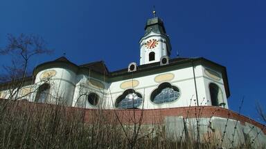 A church with a clock tower and a steeple under a clear blue sky.