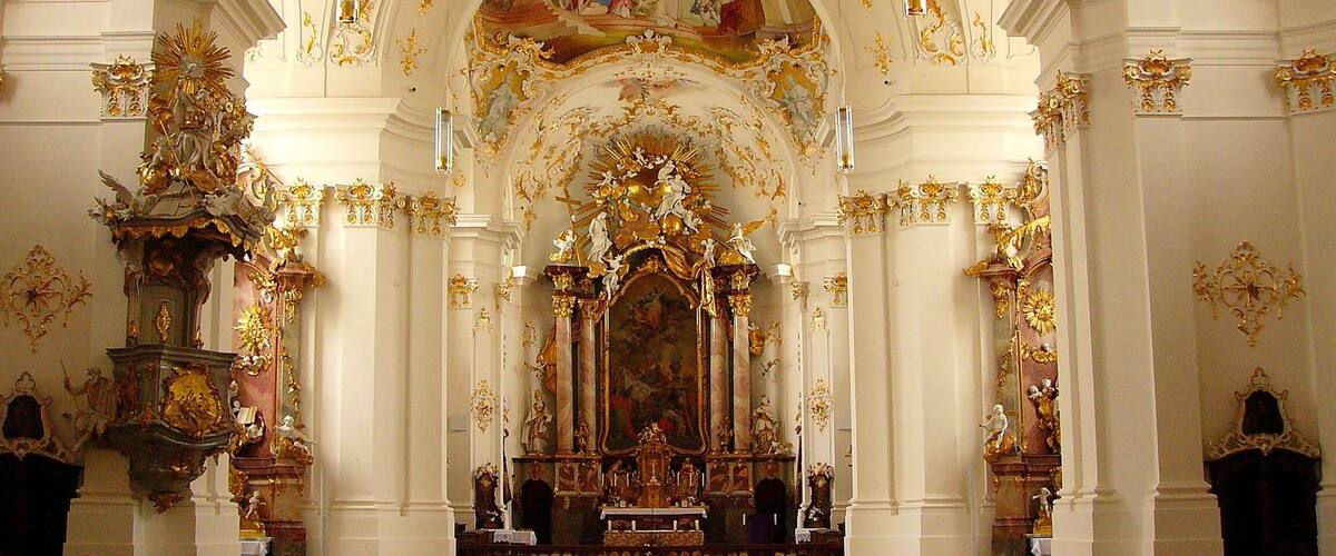 Un intérieur d’église somptueux, avec de hauts plafonds, des éléments décoratifs dorés et des fresques détaillées.