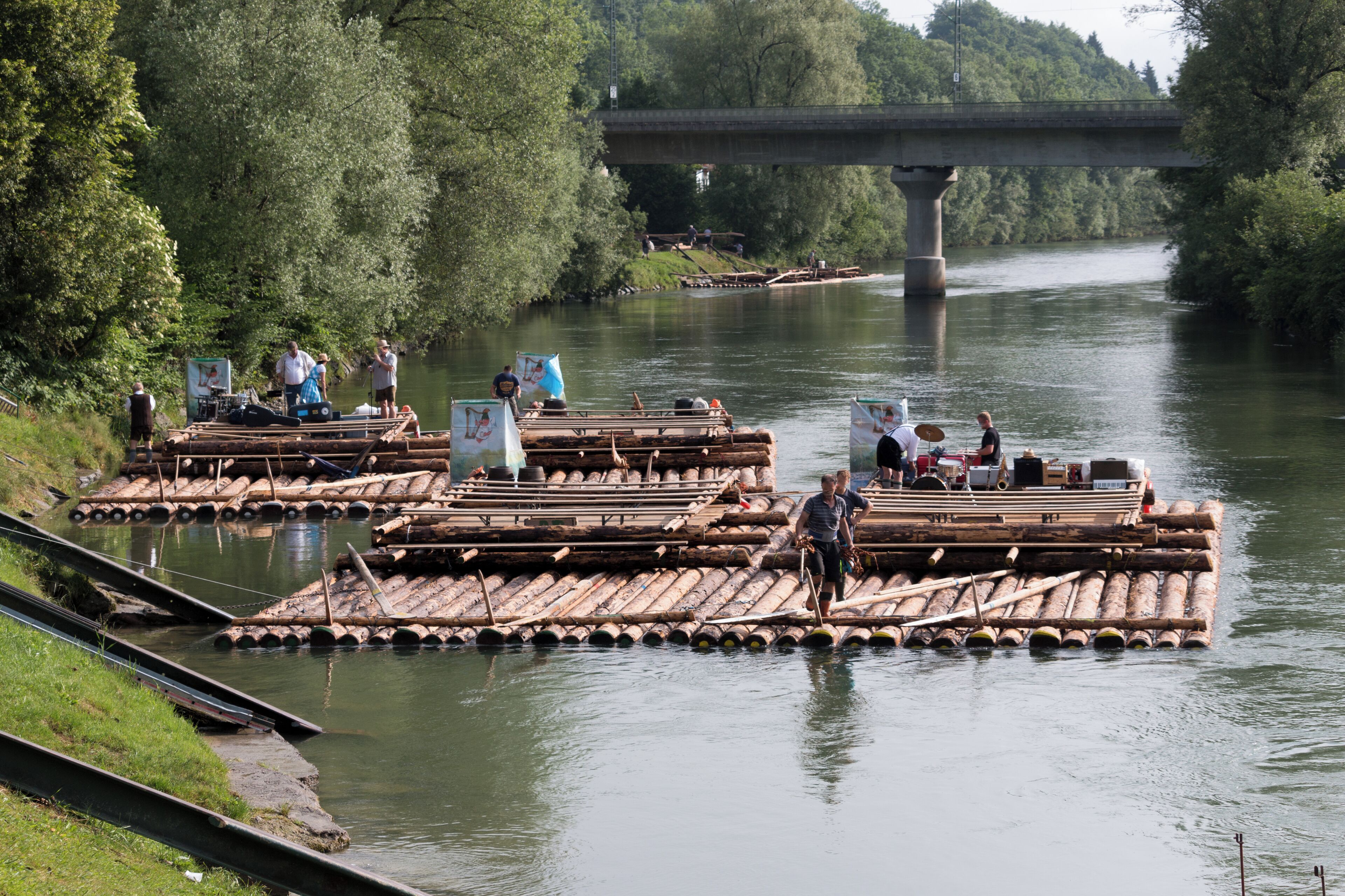 A river with wooden rafts and a bridge in the background.