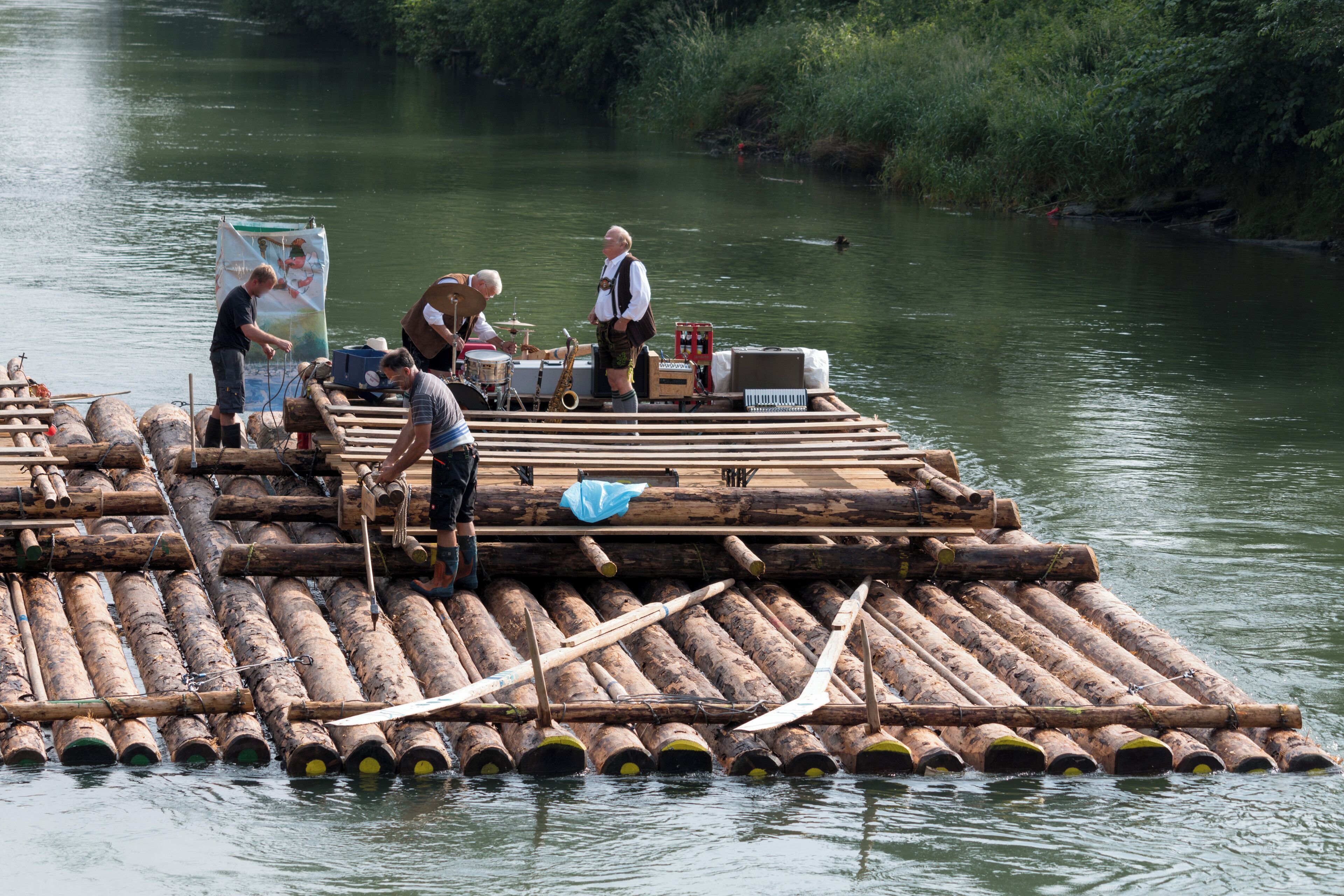 A wooden raft with musicians and equipment on a river.