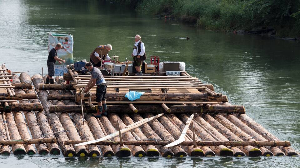A wooden raft with musicians and equipment on a river.
