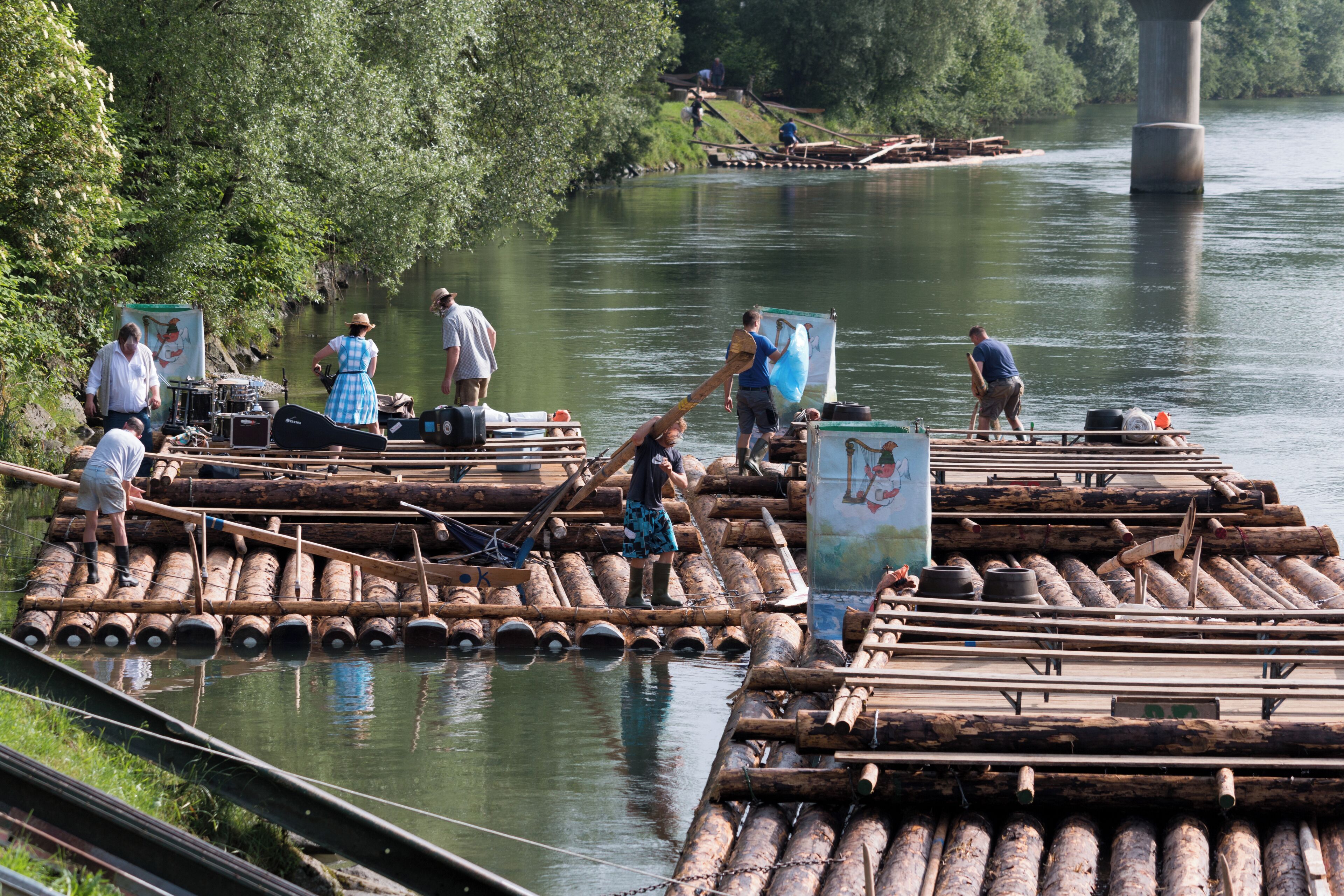 A river with wooden rafts and people on them.