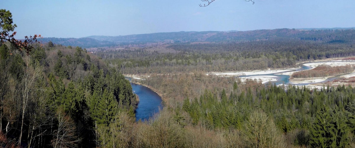 A river winding through a forested valley with a backdrop of distant hills.