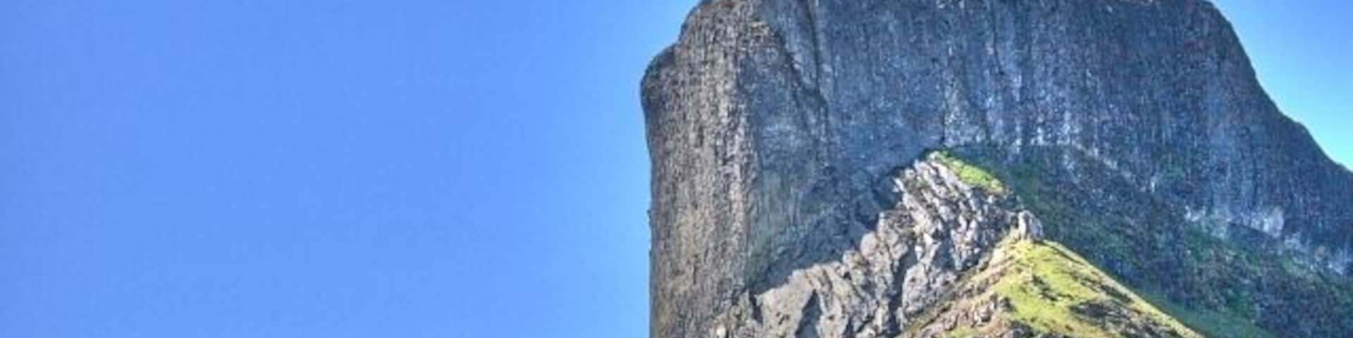 Una gran formación rocosa con un acantilado pronunciado y un cielo azul despejado.