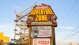 A sign for Wild Willy's Adventure Zone with a dinosaur head and a sign for Salvatore's Pizza Factory.
