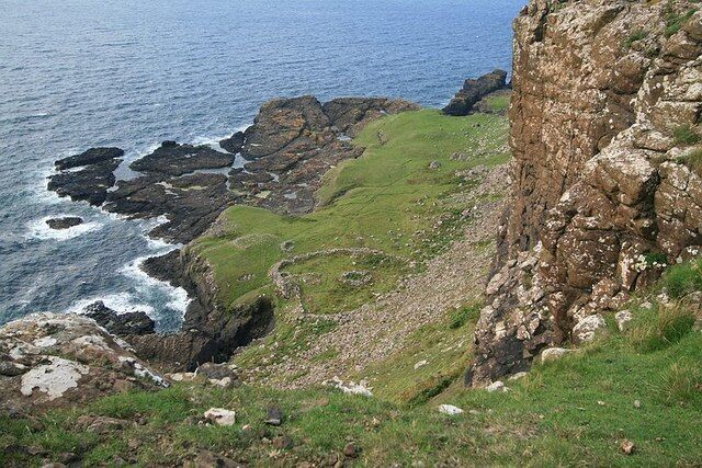 Rubha Sgorr nam Ban-naomha Remains of early christian monastic enclosure situated on a coastal terrace below steep cliffs.. This may have been an hermitage or penitential station associated with an Early Christian church at nearby Canna Harbour. 'Sgor nam Ban-naomha' is derived from the gaelic word sgór which means a flat, grassy ledge between a cliff to landward and the sea and nam Ban-naomha translating as holy women. The site is accessible from the sea only in fine weather. The construction comprises an enclosure, the drystone walling of which is 5ft thick. Within the enclosure, four structures are built against the outer wall, while three others are free standing. Of these, only a well-house and mill have so far been determined.