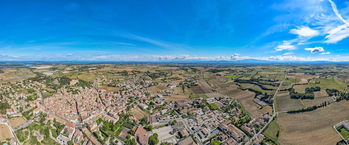 An aerial view of a town surrounded by fields and distant mountains.