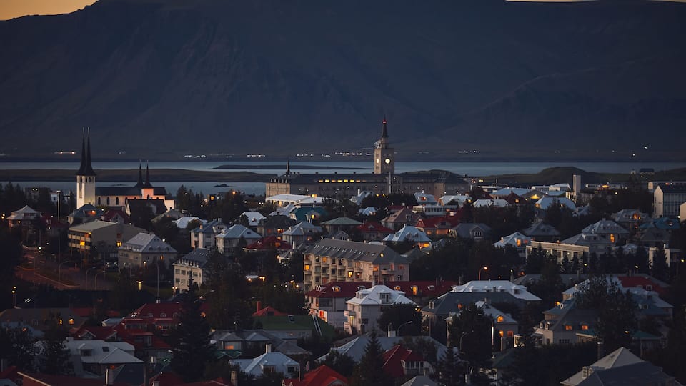 Beautiful night dusk view of Reykjavik, Iceland, aerial view with Hallgrimskirkja lutheran church, with scenery beyond the city, Esja mountain and Faxafloi bay