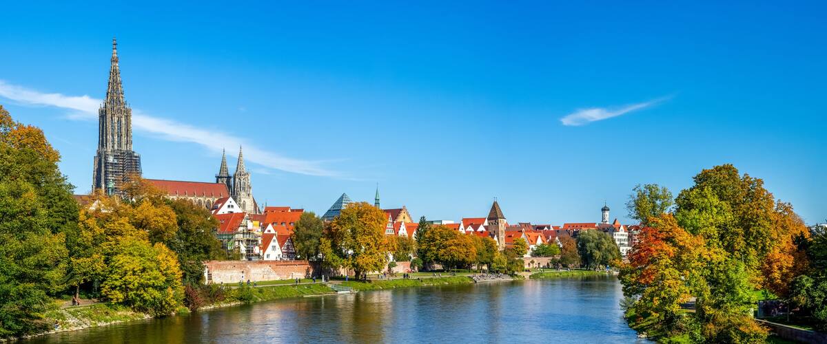 A river with a castle and a tall church tower in the background.