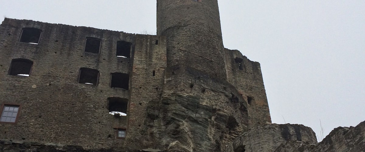 A historic stone castle with a tall tower and a flag on top.