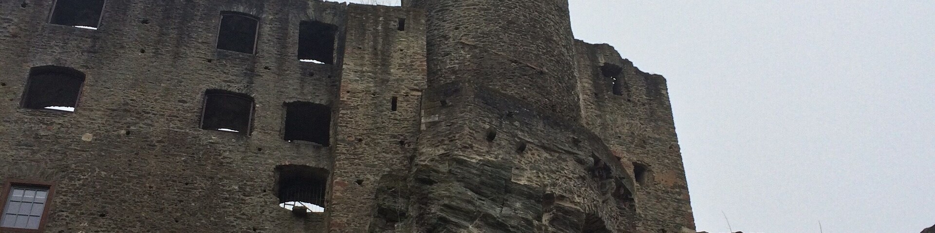 A historic stone castle with a tall tower and a flag on top.